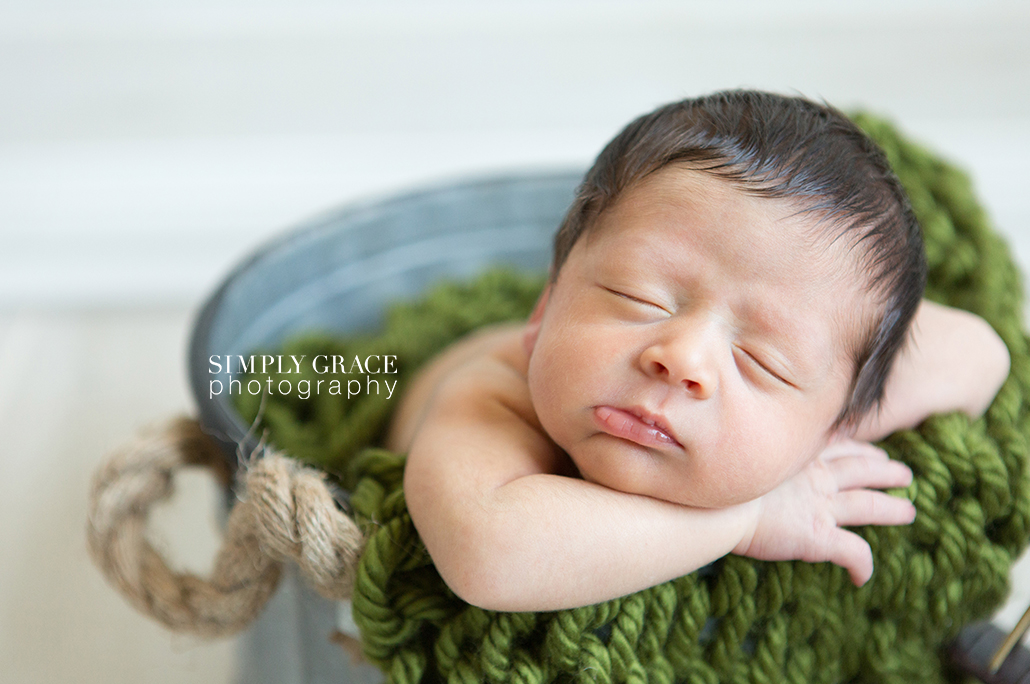 newborn in bucket and green blanket savannah simply grace photography