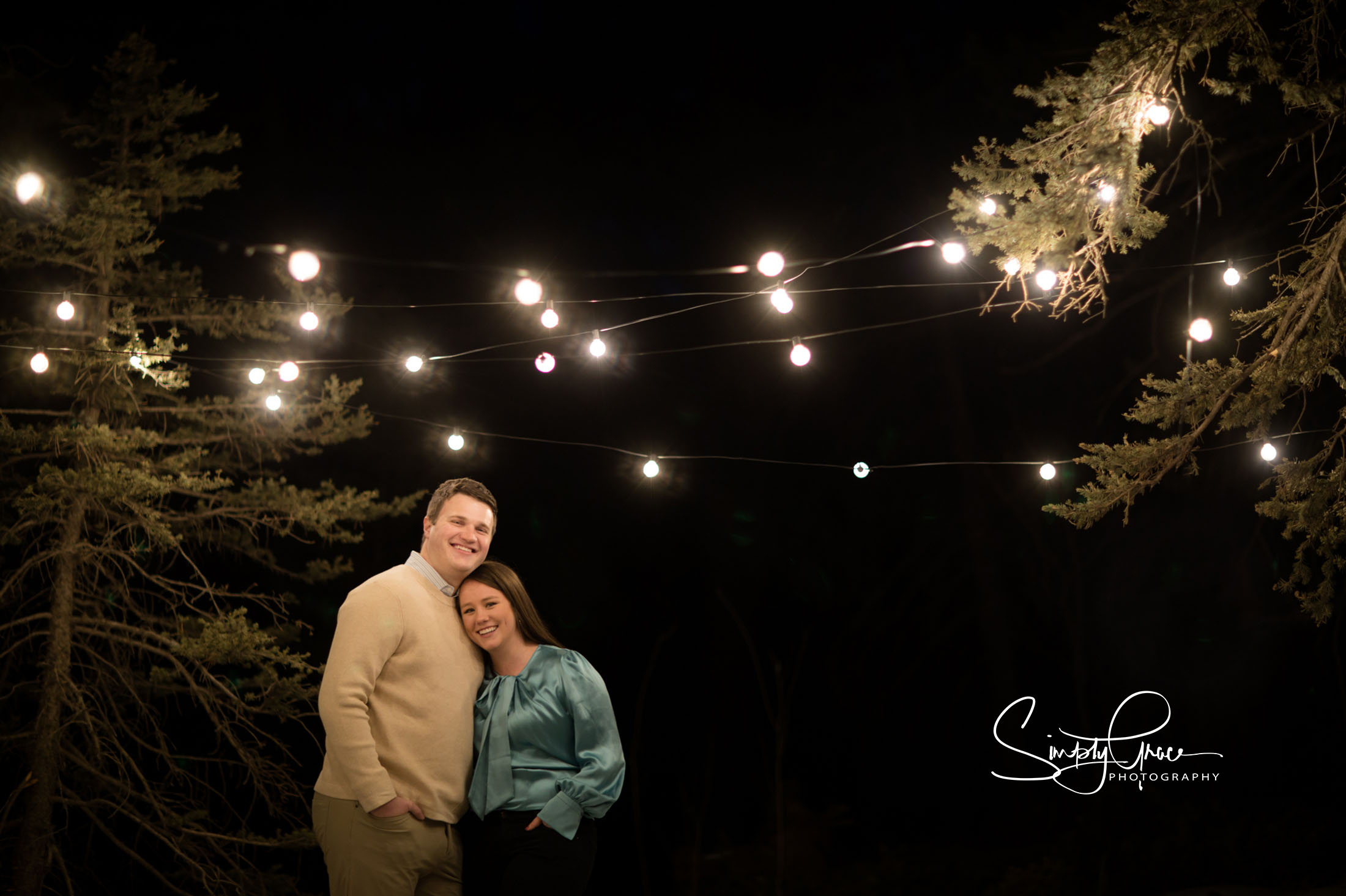 couple poses for night engagement photo in wookland park colorado