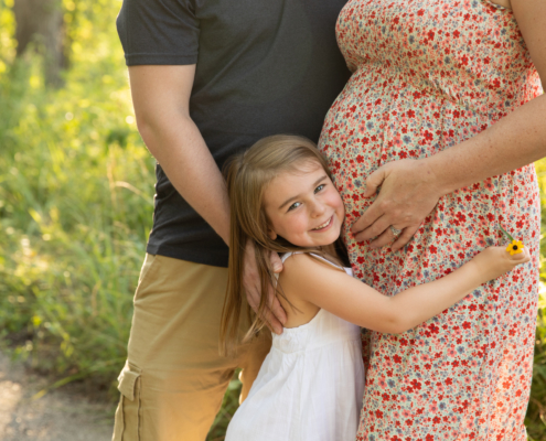 daughter hugs her mommies belly during a maternity session