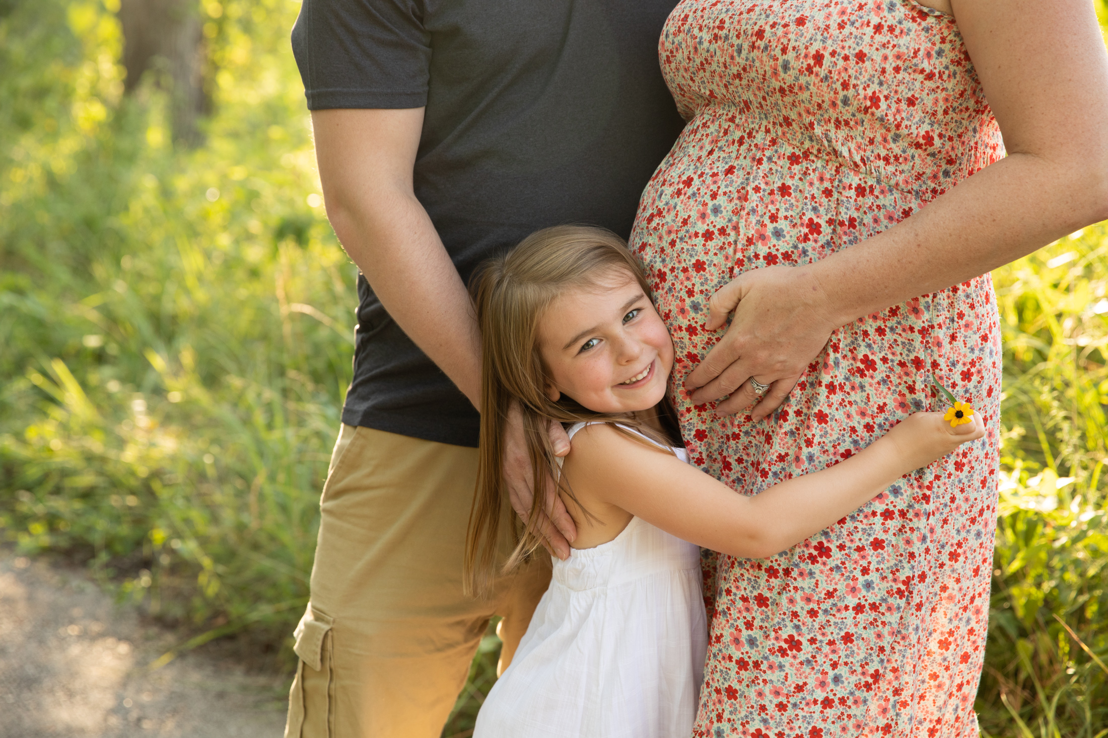 daughter hugs her mommies belly during a maternity session